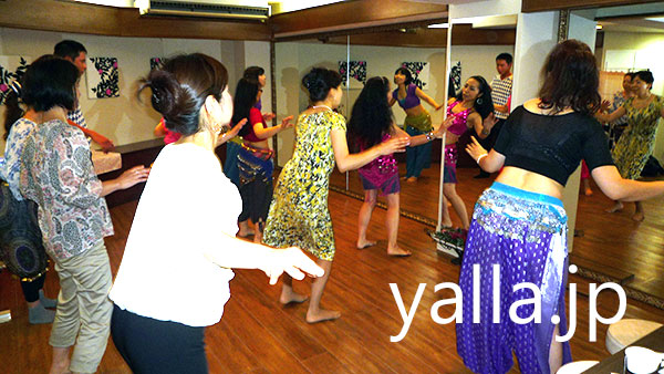 young-wemen-are-dancing-in-front-of-mirror-to-learn-bellydance-skills-with-logn-hair-instructor